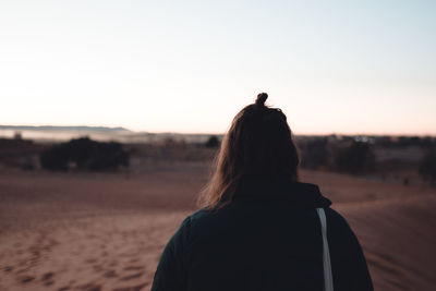 Rear view of woman standing against sky during sunset