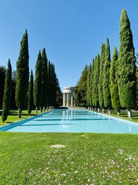 Scenic view of swimming pool in garden against clear blue sky