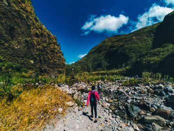 People standing on rocks by mountains against sky