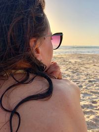 Rear view of woman wearing sunglasses at sandy beach