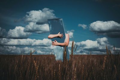 Man holding umbrella on field against sky