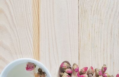 Directly above shot of dried rose flowers and cup of tea on table