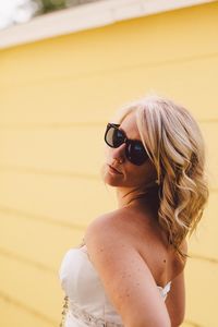 Confident beautiful woman wearing sunglasses against house