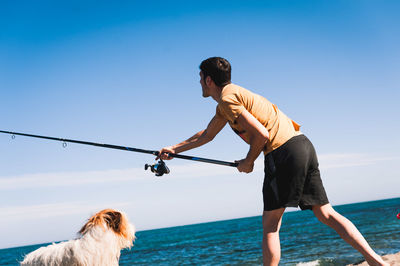 Man with dog by sea against sky