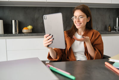 Portrait of young woman using digital tablet on table