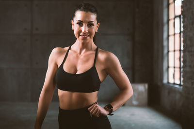 Portrait of young woman standing against wall