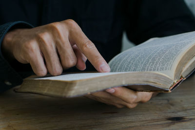 Midsection of man reading book on table