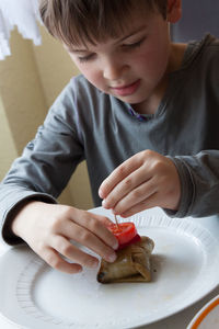 Boy preparing beef kebab in kitchen