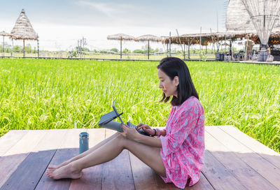 Beautiful woman working on laptop sitting on wooden deck outdoors