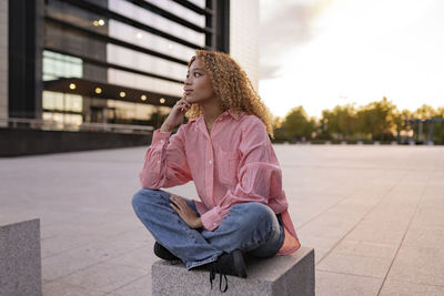 Thoughtful woman with blond curly hair sitting on seat