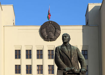 Low angle view of statue against building against clear blue sky