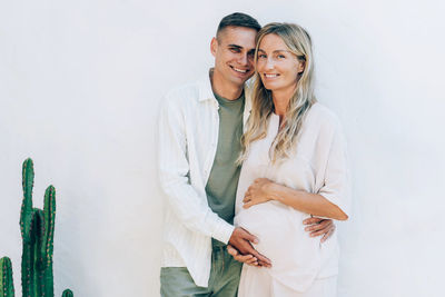 Happy married man and woman hugging pregnant belly in expectation of the birth of their baby.