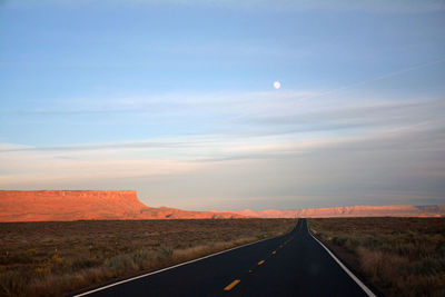 Road amidst agricultural landscape against sky