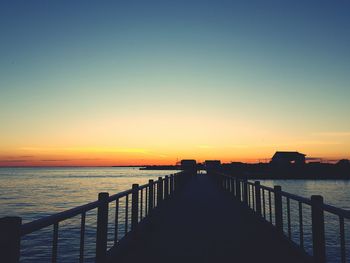 Silhouette pier over sea against sky during sunset