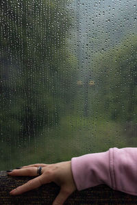 Low section of woman seen through wet glass window during rainy season