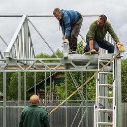 Manual workers making metallic built structure on field