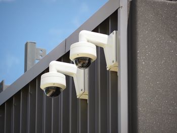 Low angle view of surveillance camera against wall of building