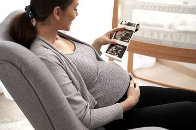 Pregnant woman holding ultrasound photograph