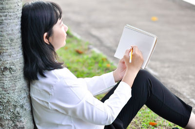 Side view of woman using mobile phone outdoors