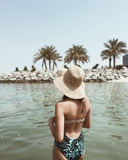 Rear view of shirtless man on beach against clear sky