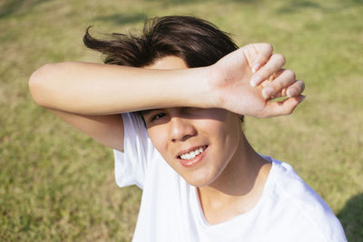 Portrait of smiling man covering eyes while sitting at park