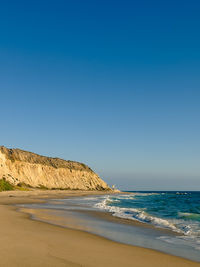 Scenic view of beach against clear blue sky