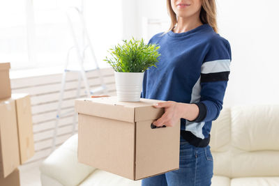 Midsection of woman carrying boxes at home