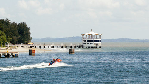 People on boat in sea against sky