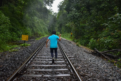 Rear view of boy walking on railroad track