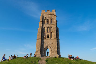 People at historical building against blue sky