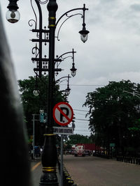 Road sign by street against sky in city