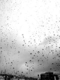 Low angle view of water drops on building against sky