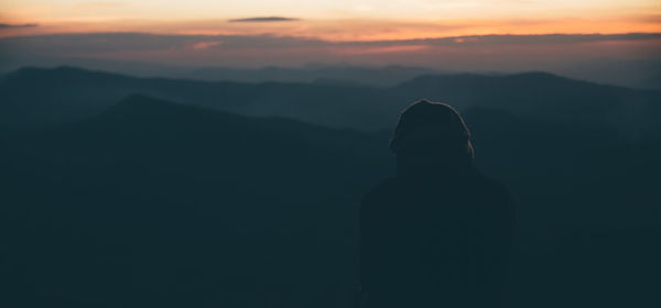 Silhouette man standing on mountain against sky during sunset