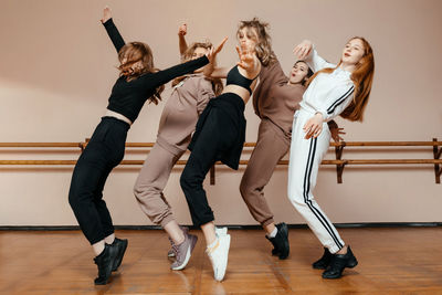 Group of girls in sportswear, performing elements of house dance in a dance studio, dancing with