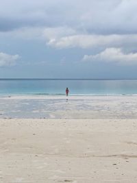 Mid distance of woman wading in sea against sky