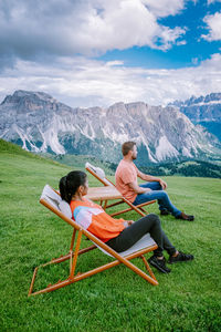 Men sitting on grass against mountains