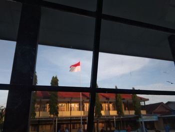 Built structure against sky seen through glass window