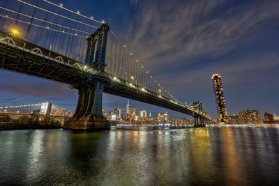 Illuminated bridge over river at night