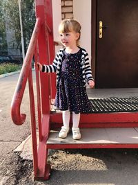 Full length of cute girl standing outside house