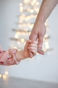 Cropped image of daughter holding fathers hand