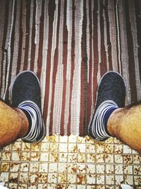Low section of person standing by red shoes