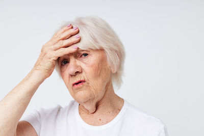 Portrait of stressed senior woman against white background