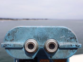 Close-up of coin-operated binoculars against sea