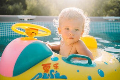 Portrait of cute baby boy sitting in inflatable ring on swimming pool