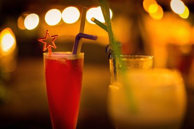 Close-up of drink in glasses against illuminated lights