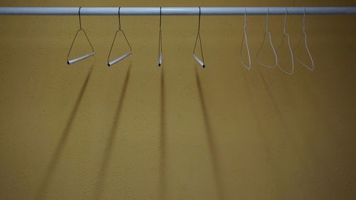 Coathangers hanging on clothes rack against yellow wall