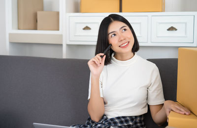 Portrait of young woman using phone at home