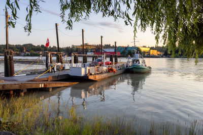 Sailboats moored in river against sky