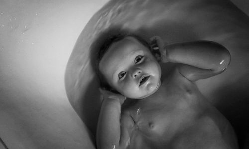 High angle view of shirtless baby boy in bathtub