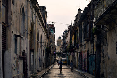 Rear view of people walking on street amidst buildings in city